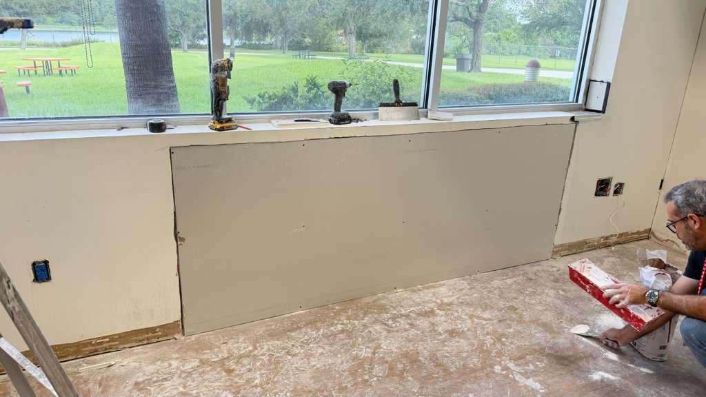 Drywall being cut and replaced along a damaged wall